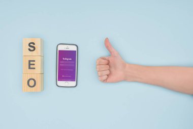 Başparmak yukarıya instagram app ile çevre smartphone üzerinde açık mavi renkli koyarak kadın üstten görünüm 