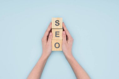 Açık mavi renkli ahşap küpleri tutan kadın seo Yöneticisi üstten görünüm 