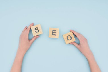 Açık mavi renkli ahşap küpleri tutan kadın seo Yöneticisi üstten görünüm 