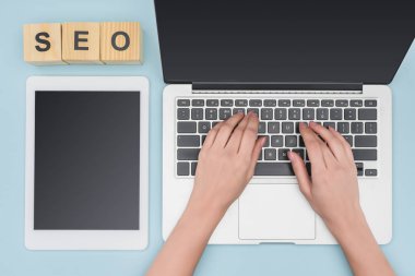 Laptop klavye gadget'ı açık mavi renkli yakınındaki yazarak kadının üstten görünüm 