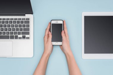 Smartphone becerikli alet yanında açık mavi renkli üzerinde tutan kadın üstten görünüm 