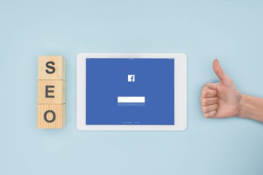 Açık mavi renkli facebook app ile dijital tablet yakınındaki başparmak gösterilmesini kadının üstten görünüm 