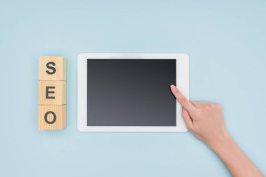 Açık mavi renkli ahşap küpleri yakınındaki dijital tablet gösteren kadın seo Yöneticisi üstten görünüm 