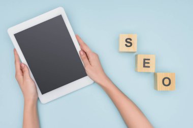 Açık mavi renkli dijital tablet ile boş perde tutan kadın seo Yöneticisi üstten görünüm 