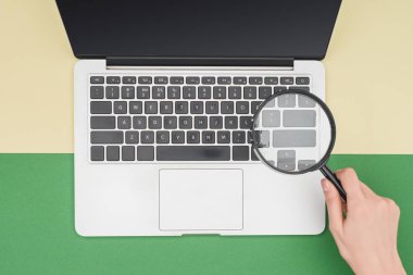 Top view of woman holding magnifier in hand above laptop  clipart