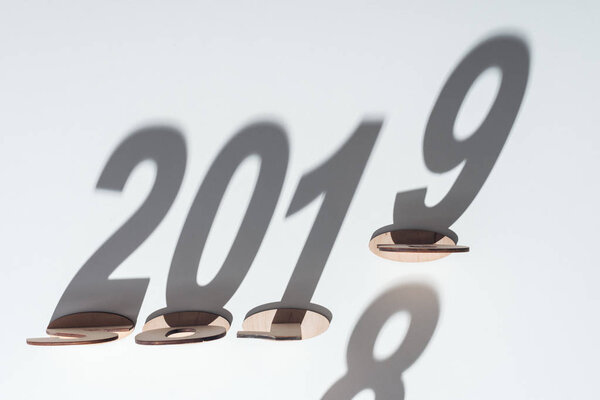 top view of wooden numbers with shadow on white background symbolizing change from 2018 to 2019
