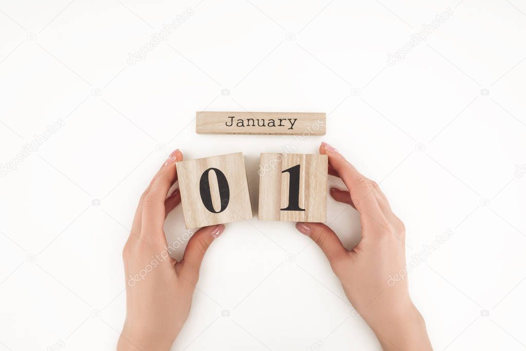 cropped view of woman holding wooden cubes with january 1st date isolated on white