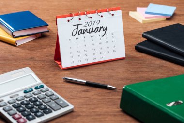 Ocak 2019 takvim, hesap makinesi ve ahşap ofis masasında Kırtasiye