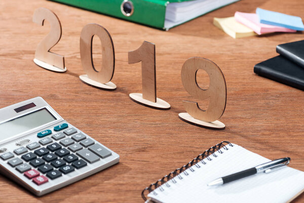 2019 date made of wooden numbers with calculator and stationery on office desk