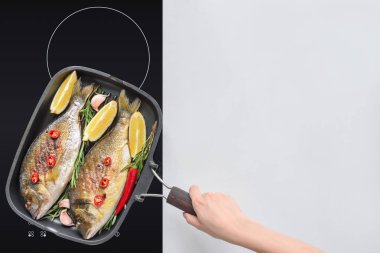cropped shot of person cooking tasty fried fish with lemon, rosemary and cherry tomatoes clipart