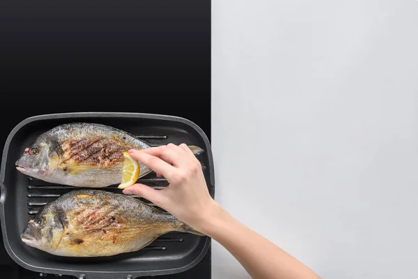 Cropped Shot Person Squeezing Lemon While Frying Fish — Free Stock Photo