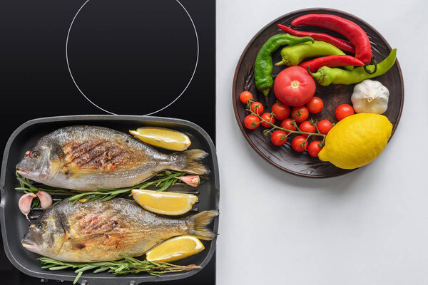 delicious fish with rosemary and lemon on grill and fresh vegetables on white 