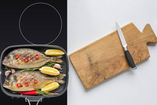 top view of delicious fried fish on electric stove and wooden cutting board with knife