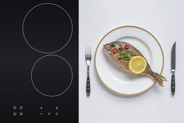 top view of delicious fried dorado fish with cherry tomatoes, rosemary and lemon on plate 