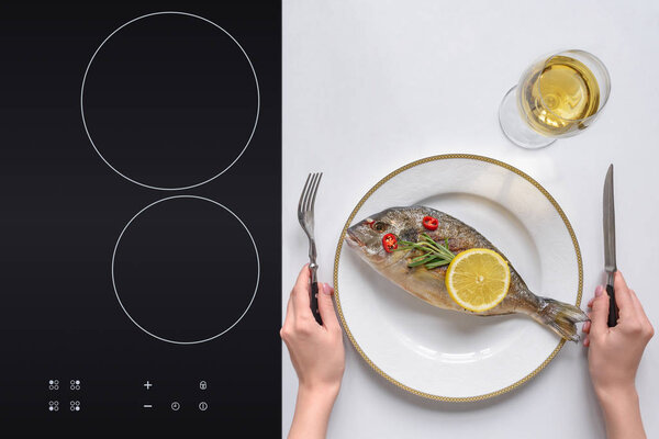 cropped shot of person holding fork with knife and eating delicious grilled fish