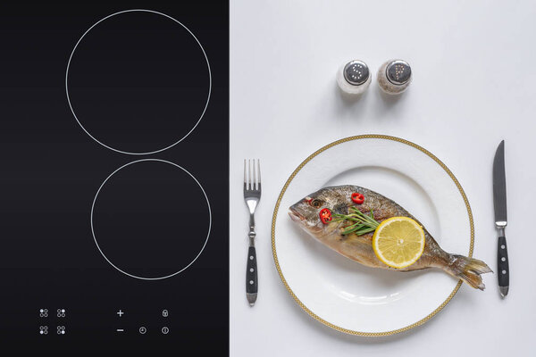 top view of delicious grilled fish with lemon, cherry tomatoes and rosemary