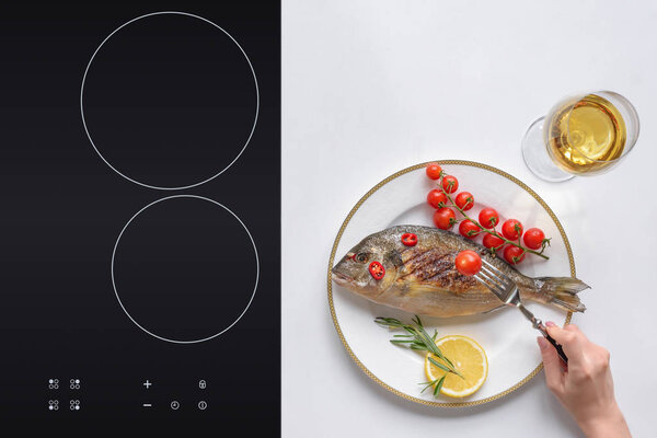 cropped shot of person eating gourmet fried fish with cherry tomatoes and rosemary