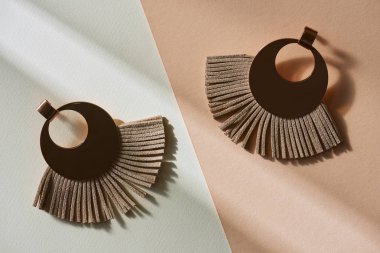 top view of beautiful luxury brown earrings on beige and white surface with sunlight clipart