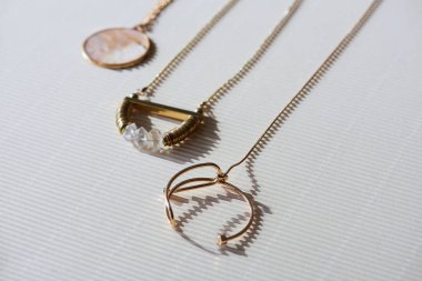 close up of beautiful luxury necklaces and round locket with marble on striped white surface with sunlight clipart