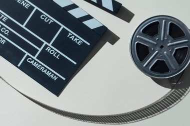 top view of clapperboard and film reel with cinema tape on grey background clipart