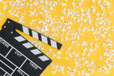 top view of clapperboard and fresh tasty popcorn isolated on yellow clipart