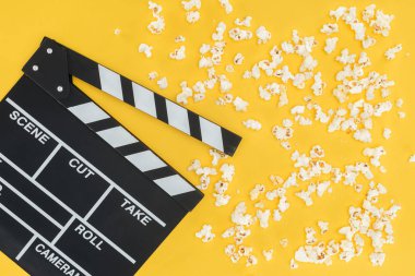 top view of cinema clapperboard and crunchy popcorn isolated on yellow clipart