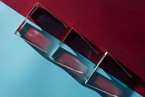 вид сверху на картон 3d очки в ряд с тенями на синем и бордо фоне
