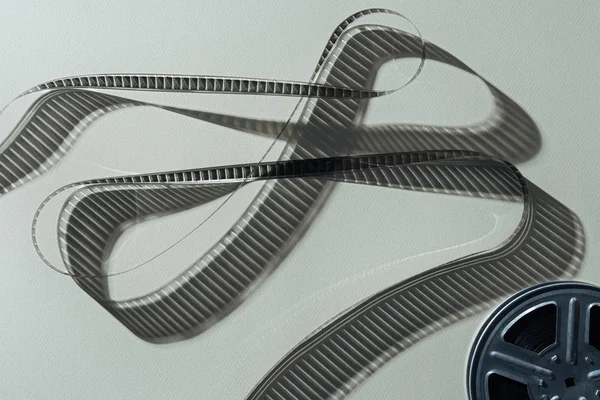 stock image top view of film reel with twisted cinema tape on grey background