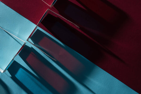 вид сверху на 3D очки с длинными тенями на синем и бордо фоне
