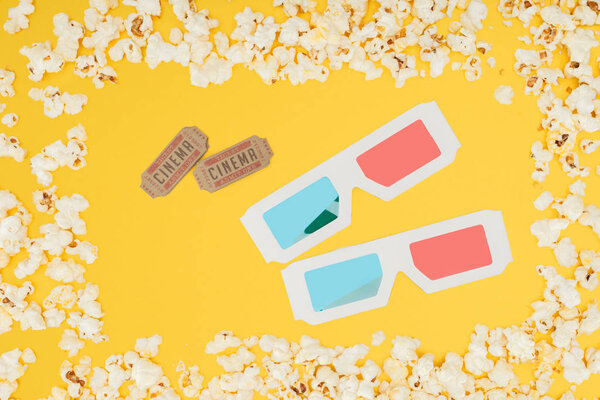cinema tickets and 3d glasses in frame made of tasty popcorn isolated on yellow