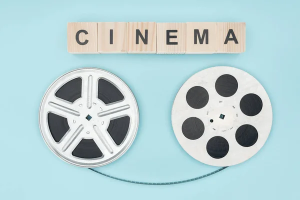 シネマ レタリングおよびフィルム リール青に分離されて間映画テープで木製キューブ — ストック写真
