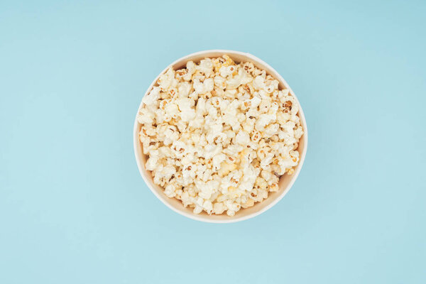 верхний вид ведра со свежим вкусным попкорном изолированы на синий
