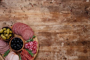 kesme tahtası zeytin, breadsticks, lezzetli jambon, salam ve otlar ile üstten görünüm dağınık baharat ahşap tablo