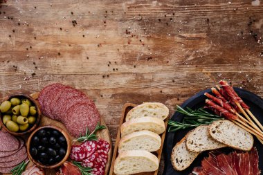 Kesme tahtaları zeytin, breadsticks, jambon, salam, ekmek ve otlar ile üstten görünüm ahşap antika tablo