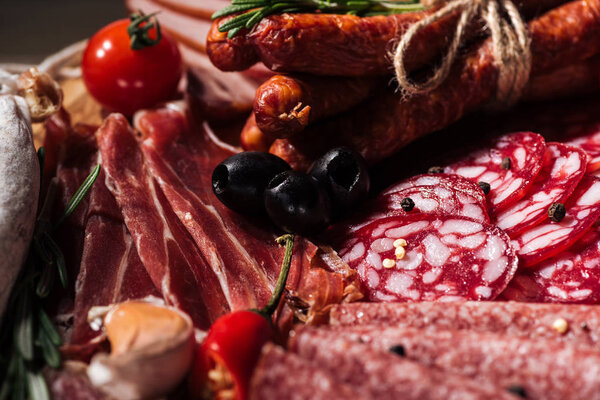 close up view of delicious sliced salami and prosciutto with vegetables and spices