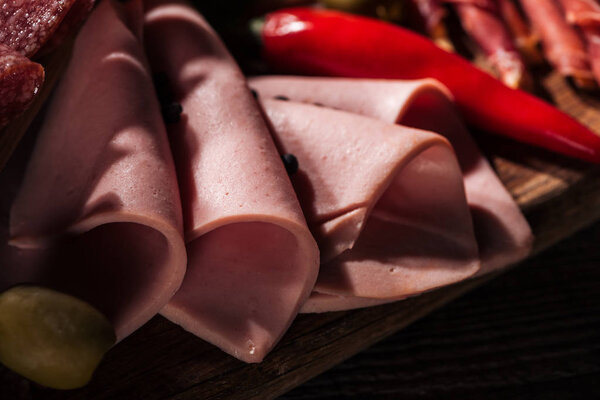 close up view of wooden cutting board with tasty sliced and wrapped ham