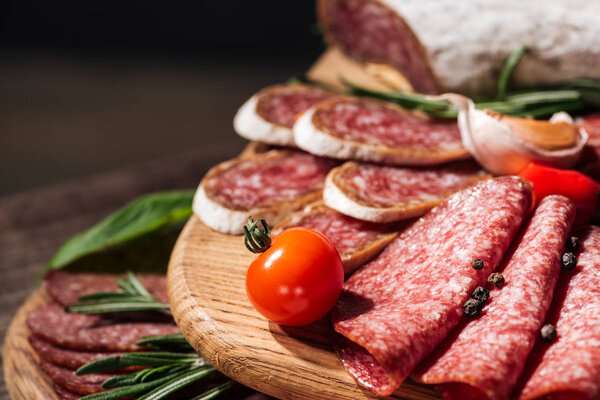 close up view of wooden cutting boards with delicious sliced salami, herbs and vegetables