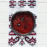 Tigela de sopa de beterraba tradicional saborosa com toalha bordada no fundo de madeira branca