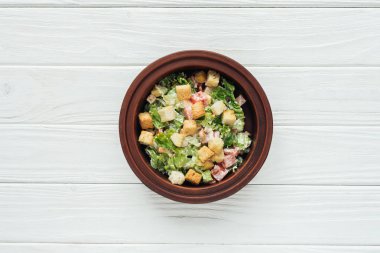 lezzetli Sezar salata kasesine croutons üstten görünüm Beyaz ahşap zemin üzerinde