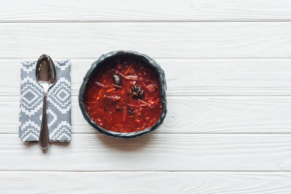 top view of traditional beetroot soup and spoon on white wooden background with copy space