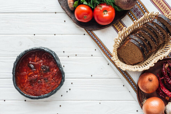 top view of traditional beetroot soup with ingredients and allspice on white wooden background