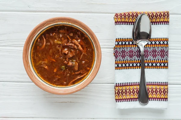 Top view of delicious traditional mixed meat soup with spoon and embroidered towel on white wooden background — Stock Image Top View Delicious Traditional Mixed Meat Soup Spoon Embroidered Towel Royalty Free Stock Photos