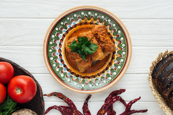 вид сверху на традиционные фаршированные капустные рулеты с петрушкой на белом деревянном фоне
