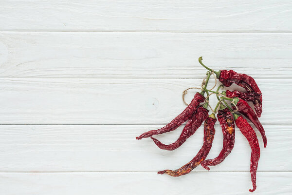bundle of red chilli peppers on white wooden background with copy space