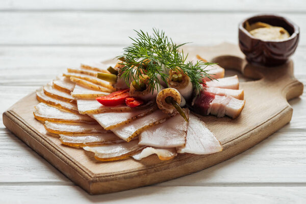 traditional tasty sliced smoked lard with dill, chilli pepper and mustard on cutting board with white wooden background