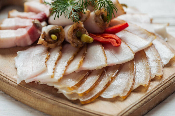 close up of traditional sliced smoked lard with dill and chilli pepper on cutting board