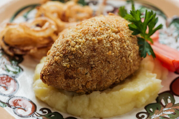 close up of tasty chicken kiev with mashed potatoes and parsley on plate with ornament