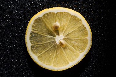 slice of fresh lemon on black background with water drops clipart