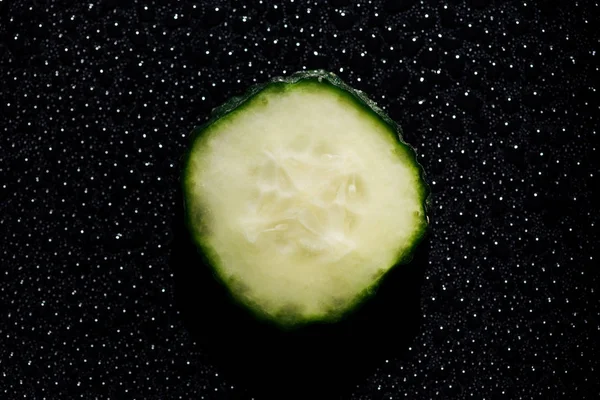 Gurkenscheibe Auf Schwarzem Hintergrund Mit Wassertropfen — kostenloses Stockfoto
