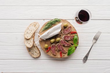 üstten görünüm ekmek parçaları üzerinde beyaz ahşap masa üstü kadeh kırmızı şarap ve çeşitli et aperatifler